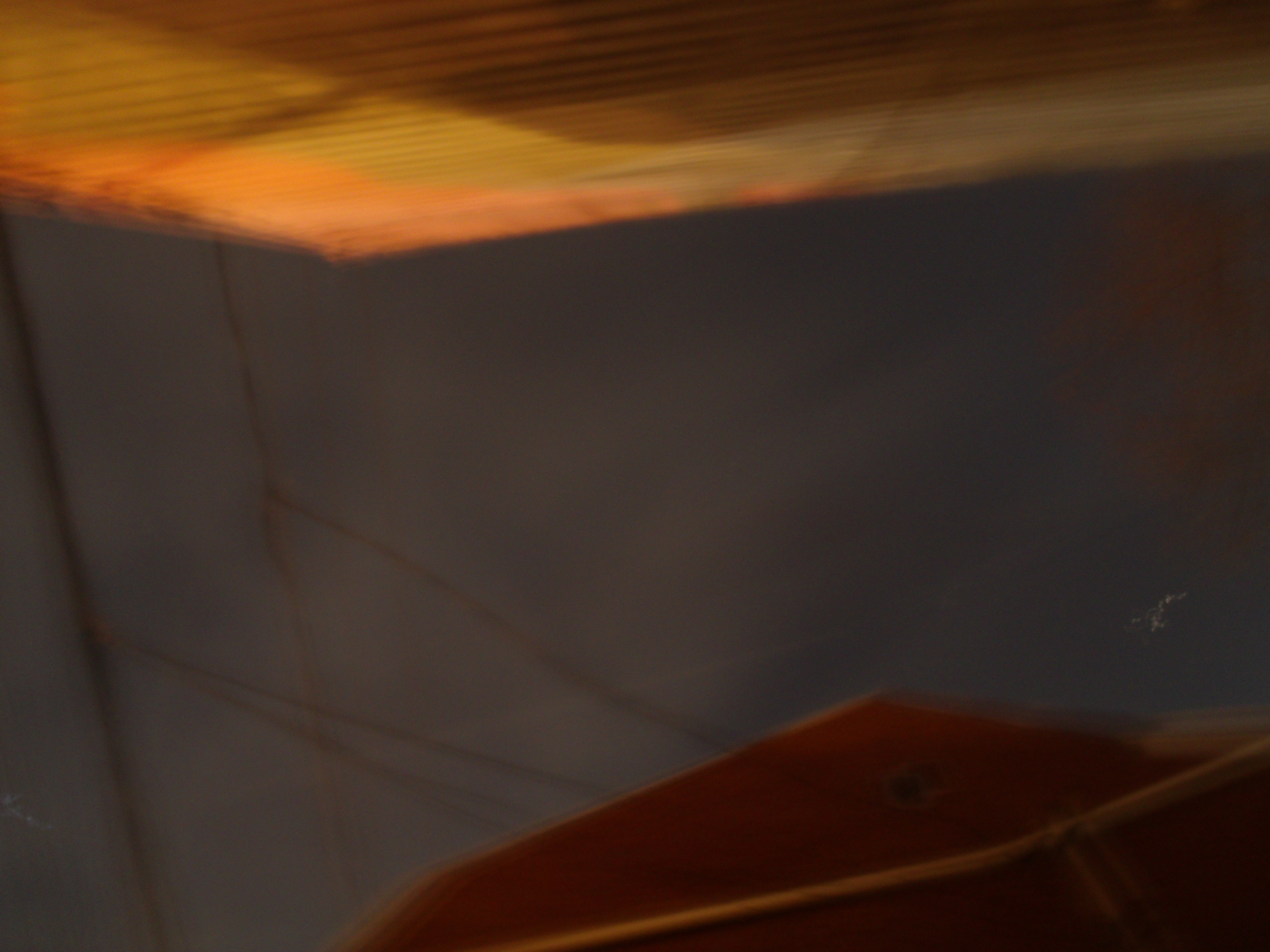 Aurore boréale clairement visible bien que blanchâtre, comme un léger voile déchiqueté et troué sur fond de ciel urbain étoilé au-dessus de notre demeure, bâtiment en brique rouge