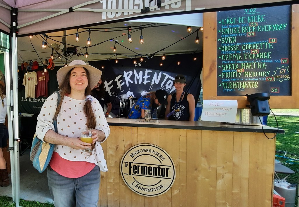 Moi devant le stand de la microbrasserie le Fermentor avec la bière que je viens d'acheter, la Crème d'orange. Un délice.