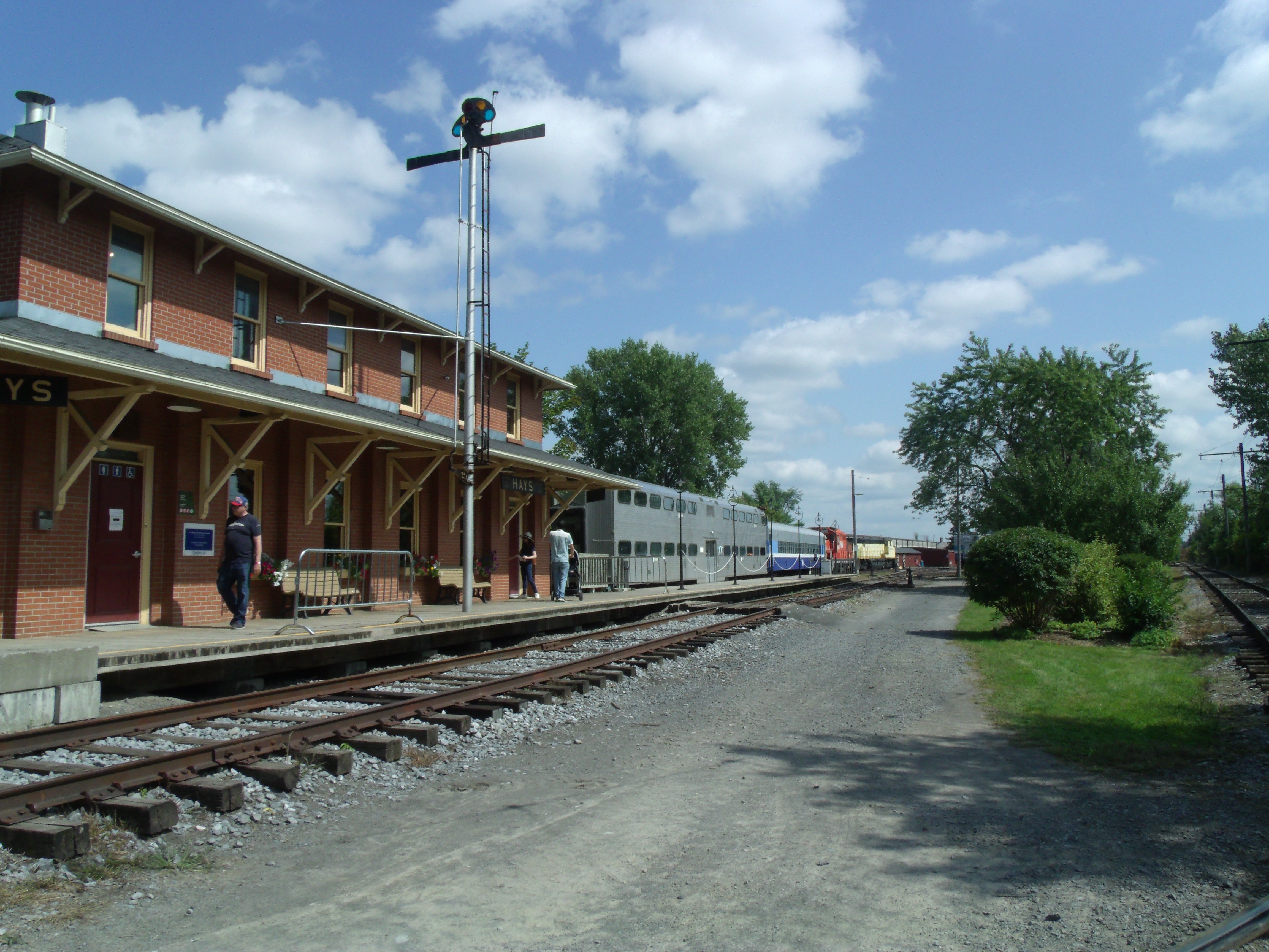 Une gare et le chemin de fer qui passe devant, au loin des trains garés.