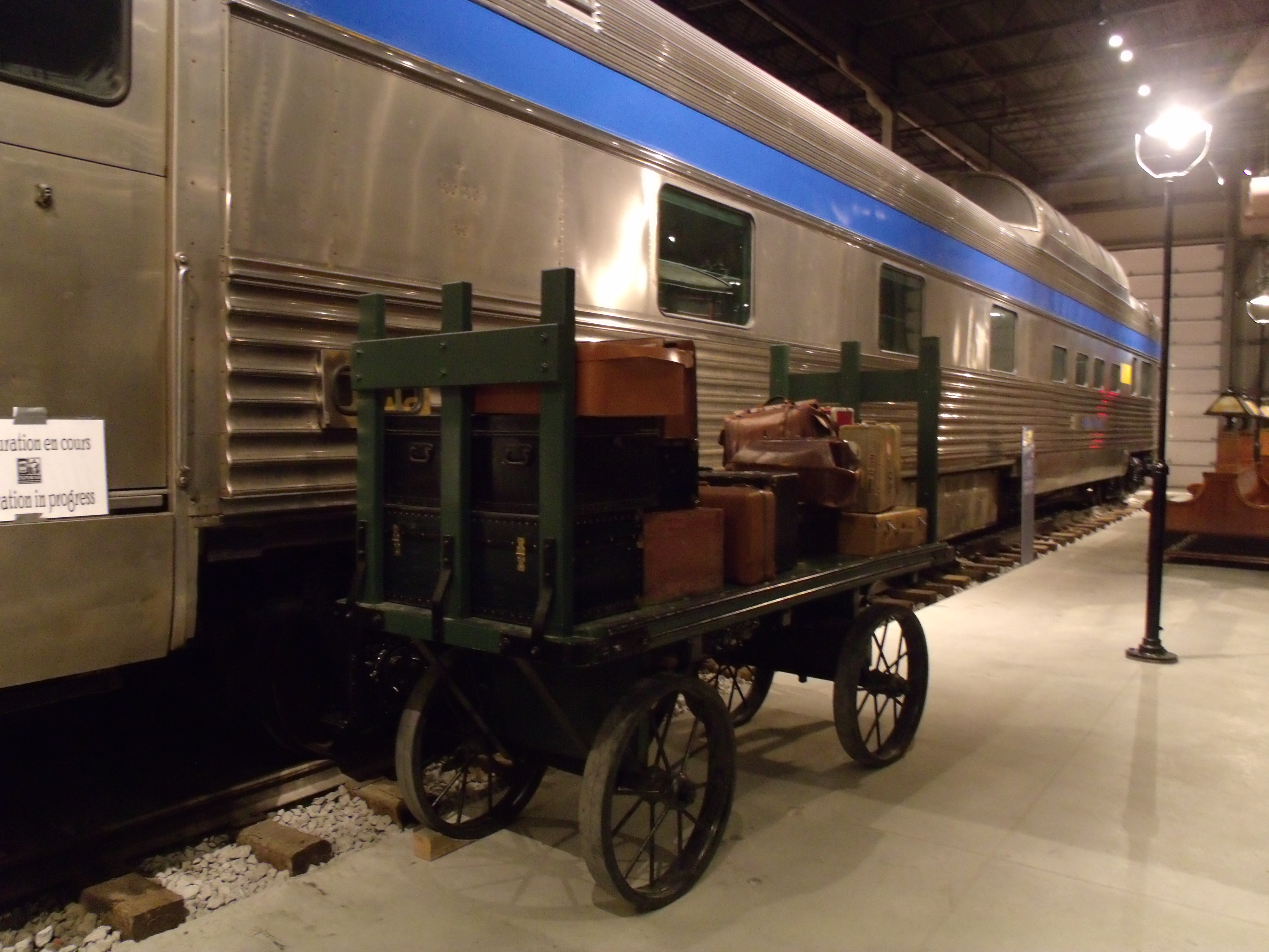 Un chariot à bagage bien rempli devant un train garé