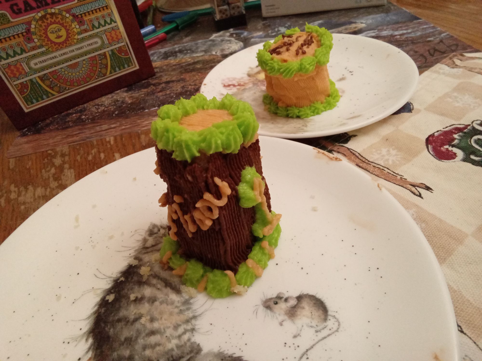 Close up d'un des minis gâteaux enrobés de crémage au beurre et chocolat et tracé en orange pâle Miaou sur l'une des quatre faces et le chiffre 1 en vert et orange en arrière-plan, le deuxième petit gâteau aux couleurs du blog vert et orange pâle avec logo sur le dessus tracé au chocolat de la Miaougraphie.