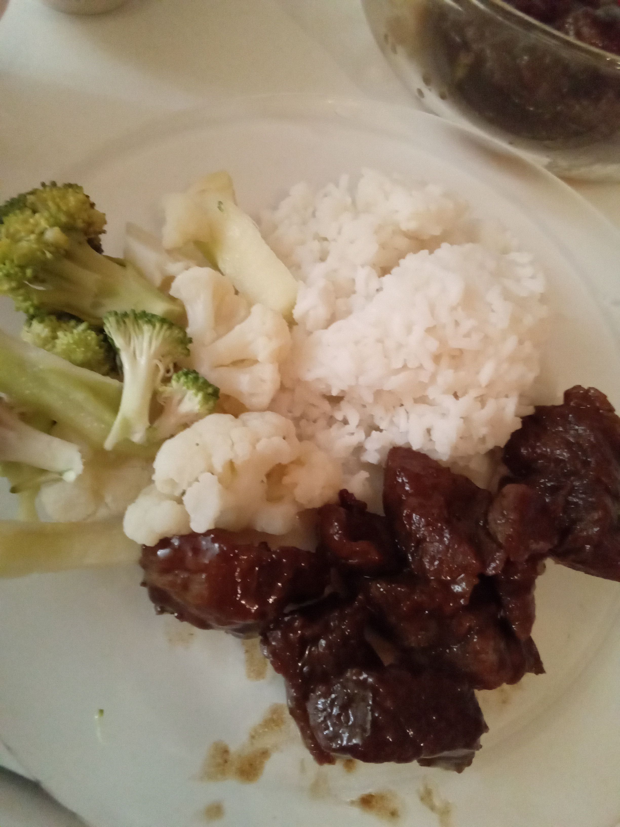 Une assiette vue en plongée de boeuf teriyaki, accompagné de chous-fleurs et brocolis blanchis et de riz blanc.